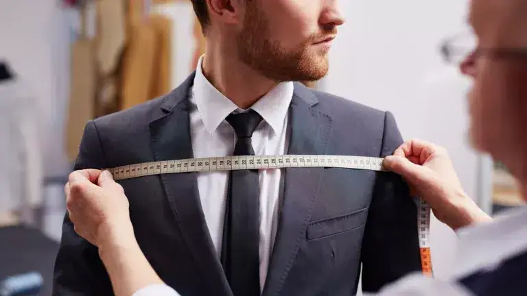 Mid,Section,Portrait,Of,Tailor,Fitting,Bespoke,Suit,To,Model